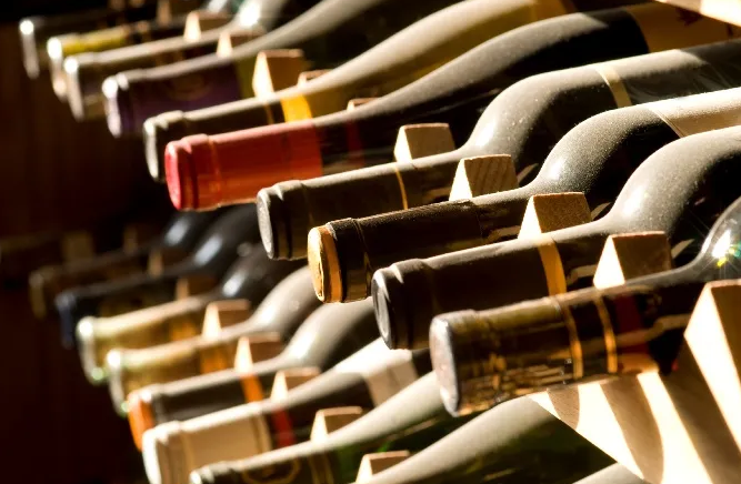 Image shows bottles of wine stacked horizontally on wooden shelves.